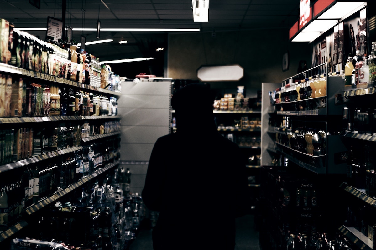 teen in hoodie in liquor store aisle