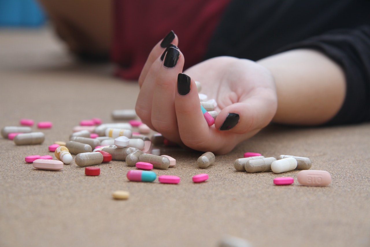 photo of girl on floor with pills in her hand