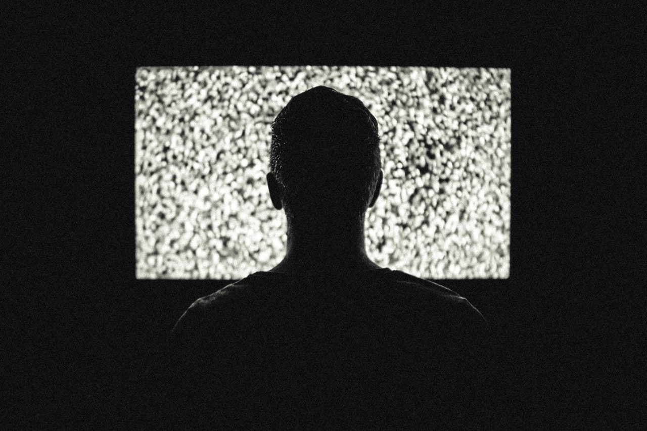 male in front of tv with static on screen