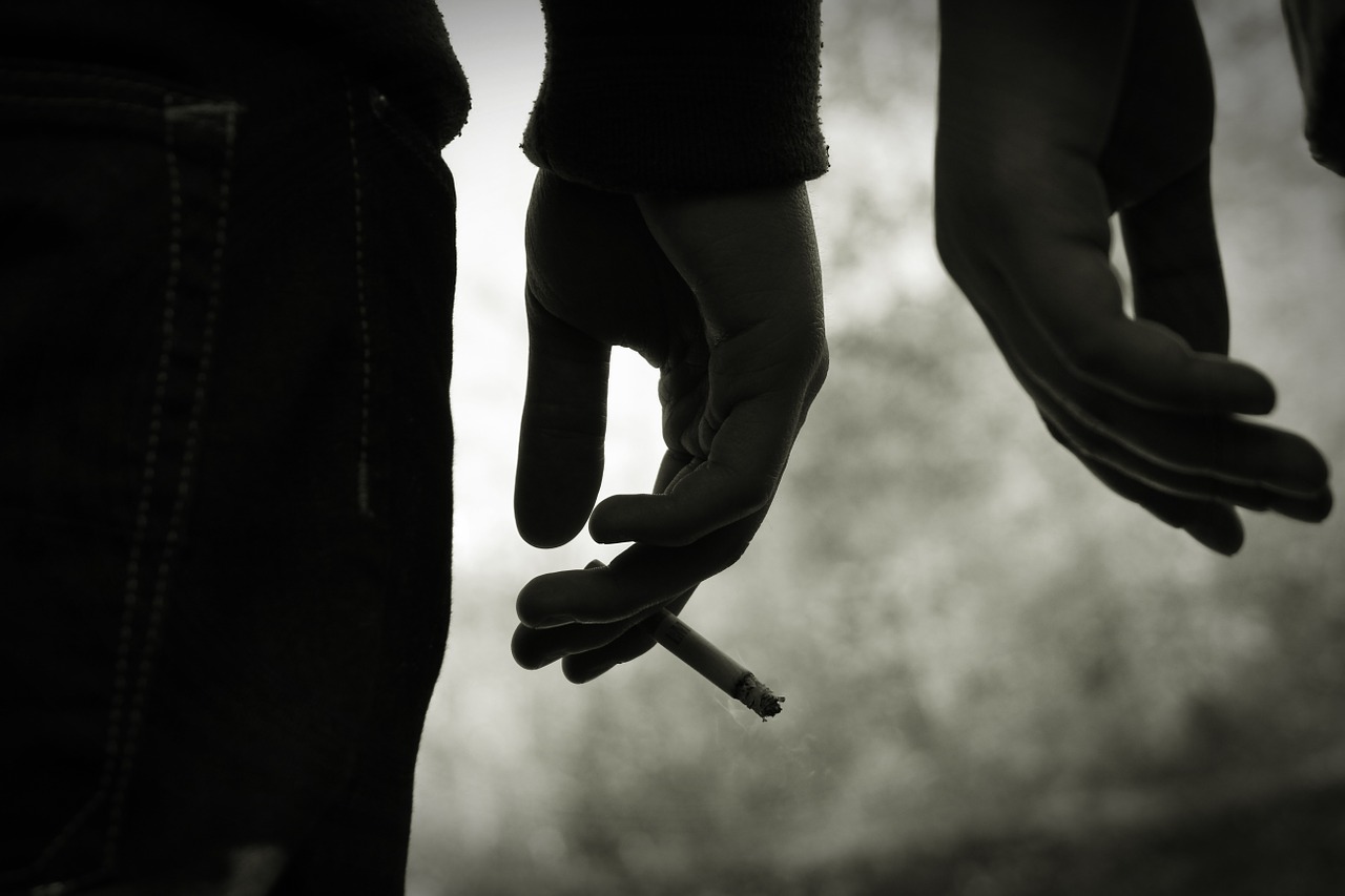 photo of teen boy holding cigarette in hand