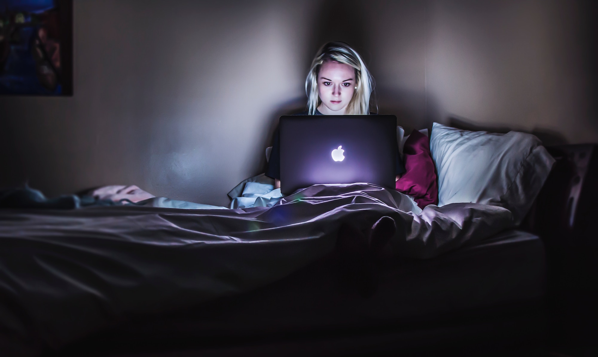 teen girl in bedroom with laptop on her bed