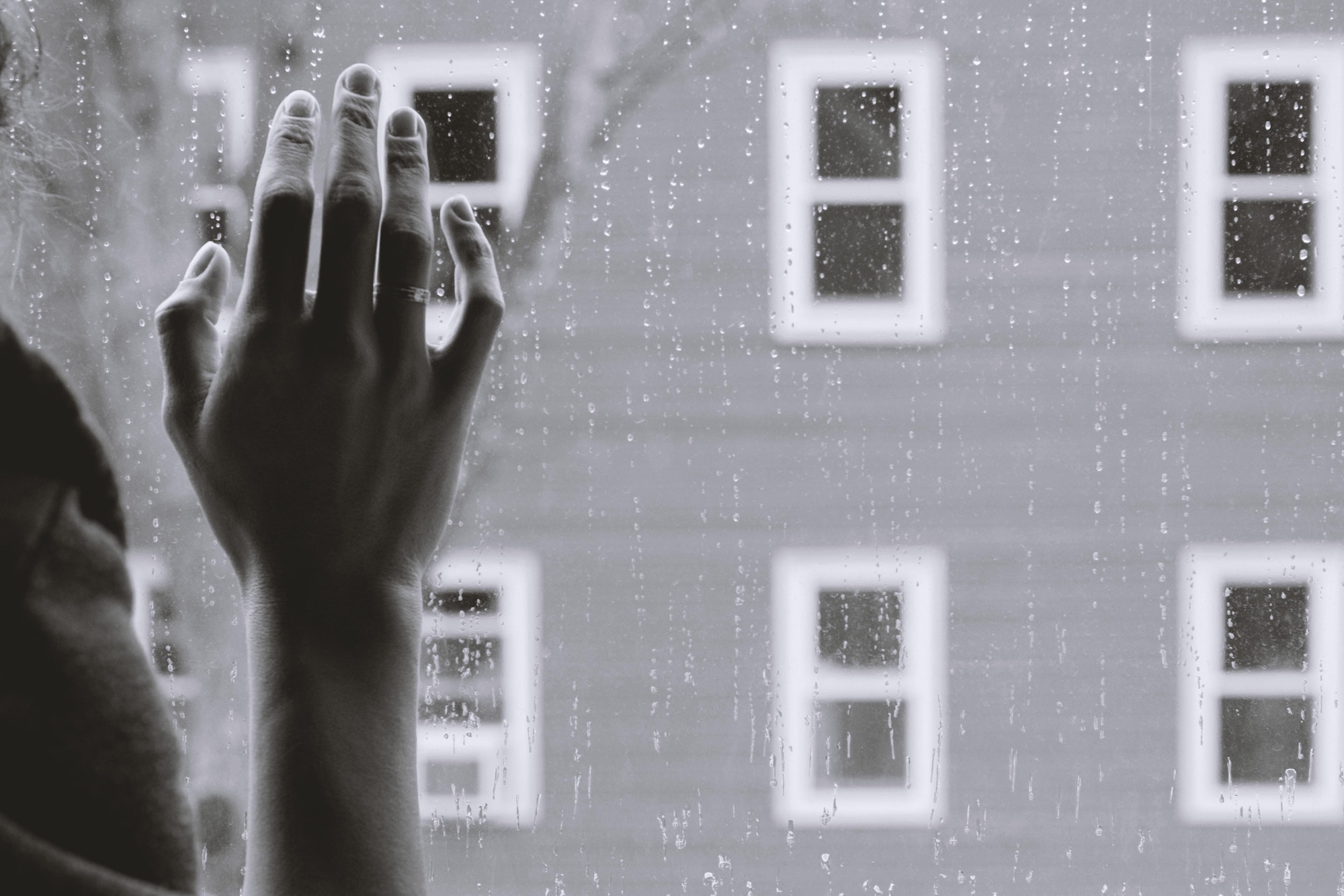 suicide teen hand on glass with rain falling down